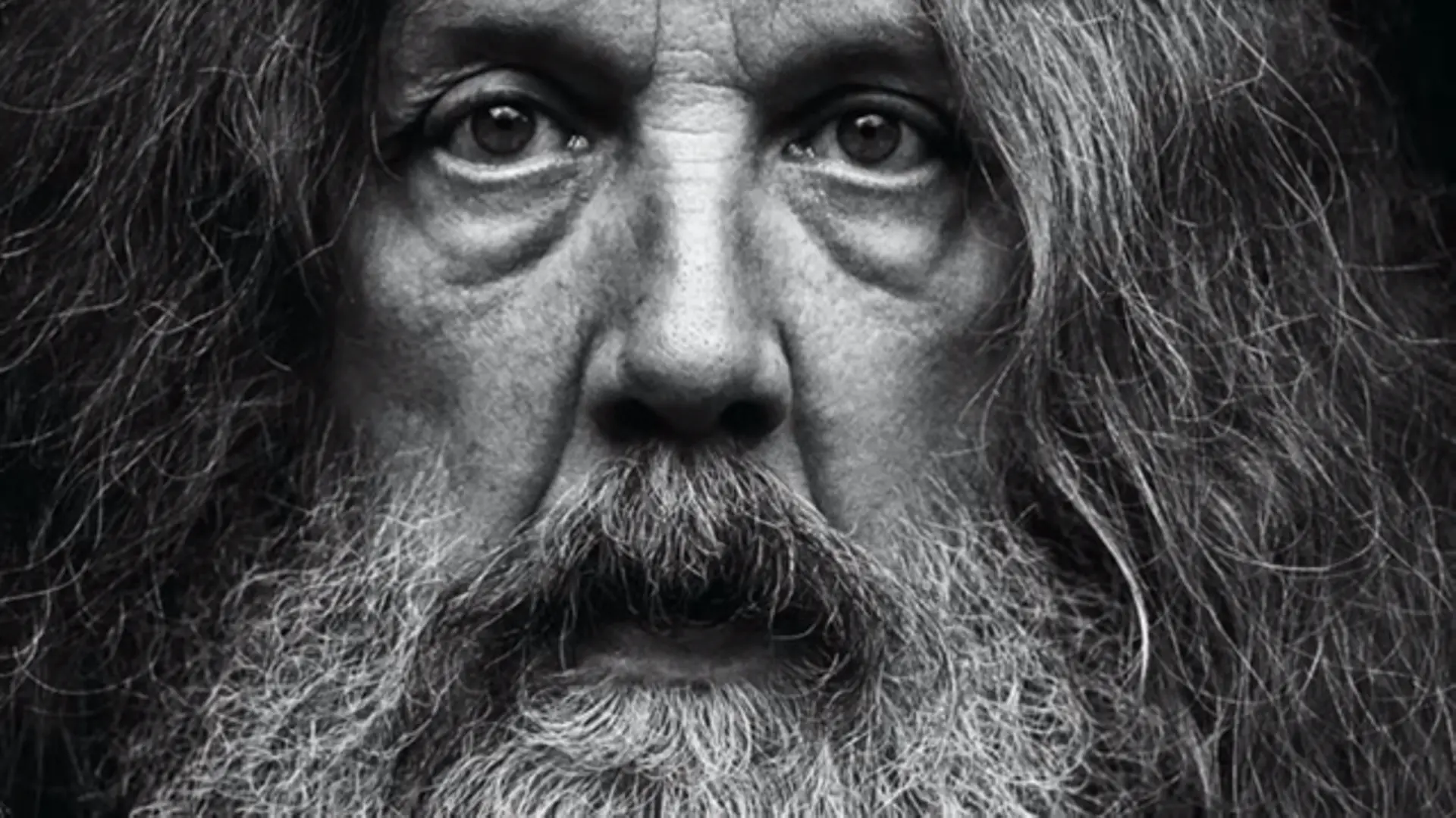 IMAGEN DEL ESCRITOR: ALAN MOORE EN BLANCO Y NEGRO. ZOOM DE SU ROSTRO, PELO LARGO Y BARBA LARGA.